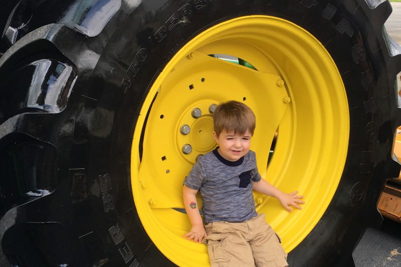 kid sitting in a huge construction tire at touch a truck